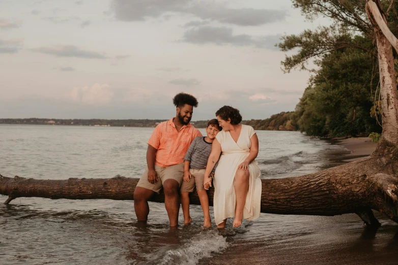 a man and woman sitting on a log in the water, by Carey Morris, pexels contest winner, portrait of family of three, full figured, diverse, from wheaton illinois