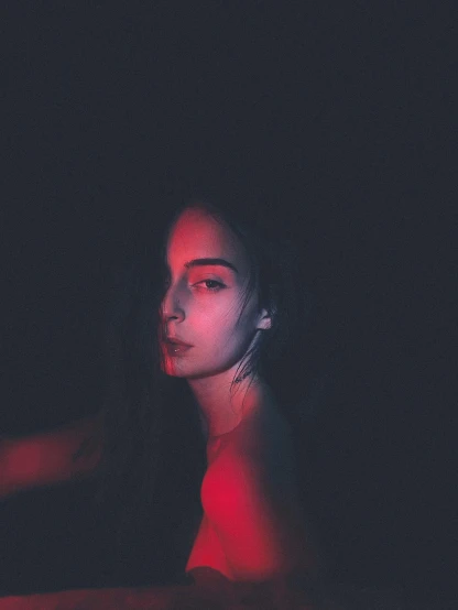 a woman sitting on top of a bed in the dark, an album cover, inspired by Elsa Bleda, pexels contest winner, human face with bright red yes, profile pic, infrared, standing with a black background