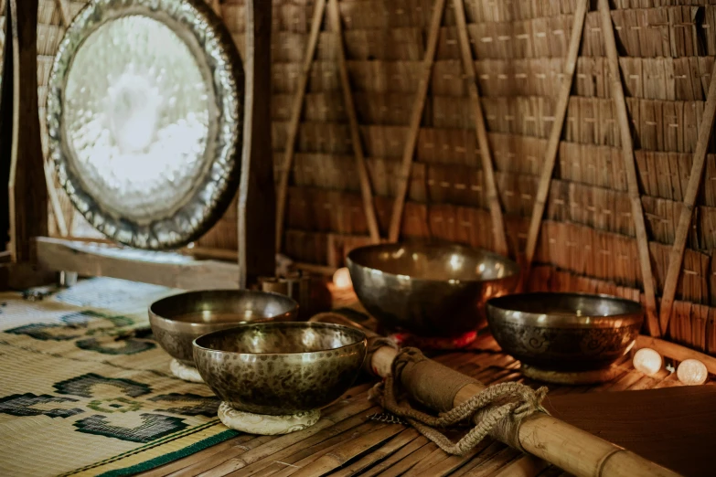 a group of bowls sitting on top of a table, inspired by Gong Kai, trending on unsplash, hurufiyya, ancient interior tent background, cambodia, an instrument, metallic