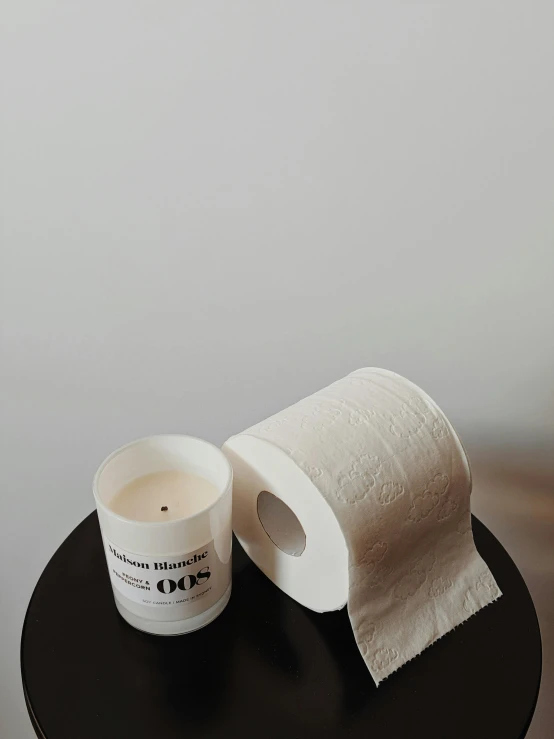 a coffee cup sitting on top of a table next to a roll of toilet paper, by Nina Hamnett, baroque, candle, product view, embossed, off white