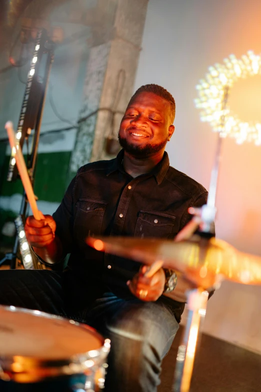 a man sitting in front of a drum set, godwin akpan, anthony pafford, background, holiday season