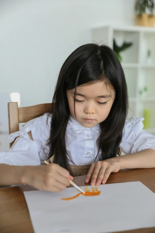 a little girl is painting on a piece of paper, inspired by Pacita Abad, pexels contest winner, process art, orange and white color scheme, asian woman made from origami, realistic cute girl painting, paper quilling