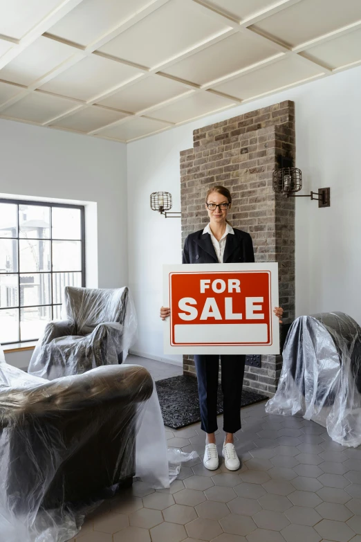 a woman holding a for sale sign in a living room, pexels contest winner, big open floor 8 k, woman in black business suit, low density, moving