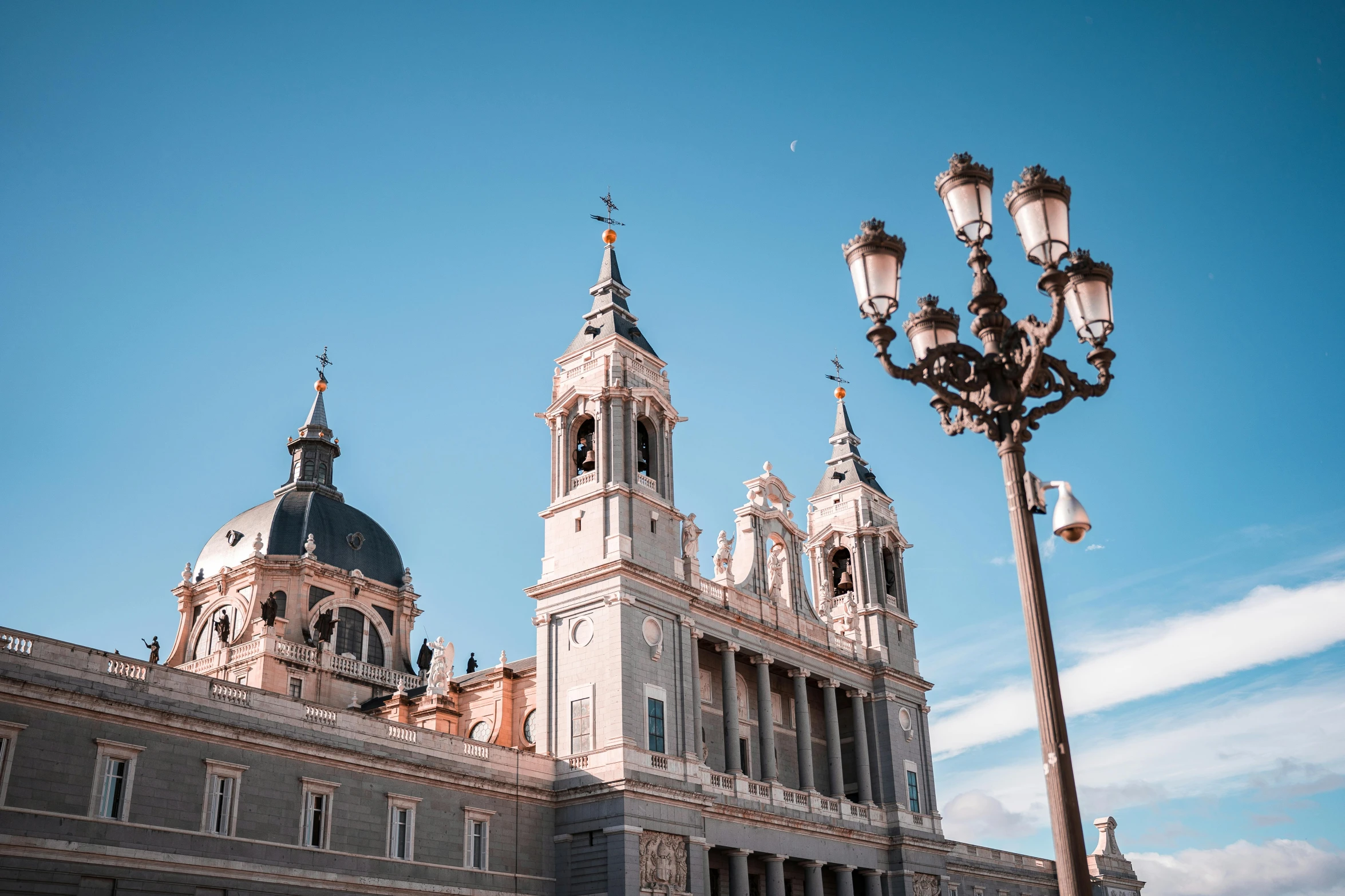 a large building with a clock tower next to a street light, inspired by Christopher Wren, pexels contest winner, baroque, madrid, with great domes and arches, pearly sky, square