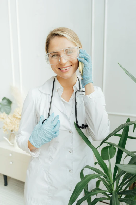 a woman in a lab coat talking on a cell phone, plants in glasses, trending photo, scrubs, wearing gloves