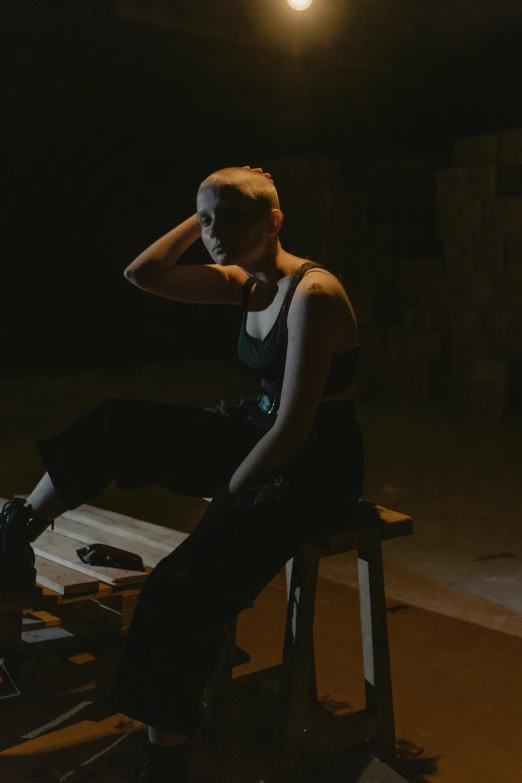 a woman sitting on top of a wooden bench, a portrait, inspired by Elsa Bleda, unsplash, realism, in a pitch black room, die antwoord music video, cardboard, performance