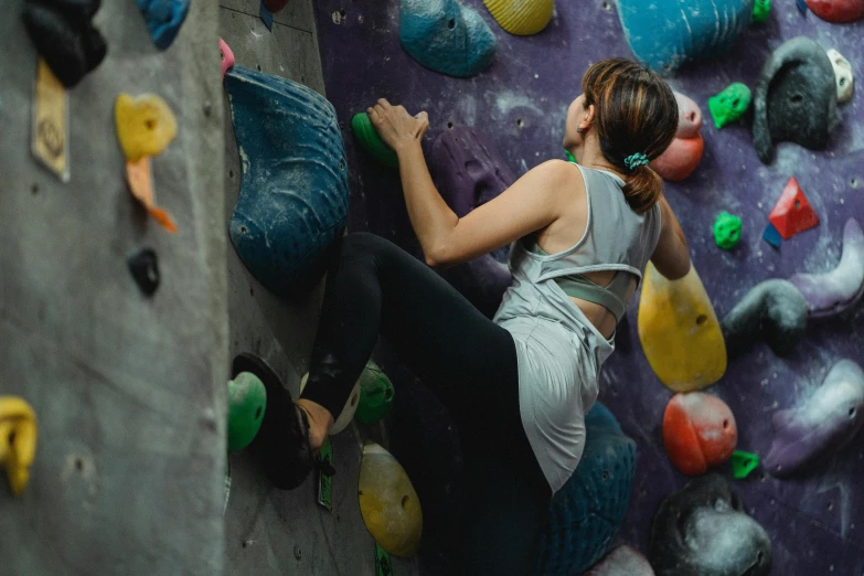 a woman climbing up the side of a rock wall, pexels contest winner, in a gym, 🦩🪐🐞👩🏻🦳, central hub, mid 2 0's female