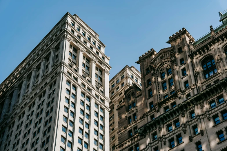 a couple of tall buildings next to each other, by Greg Rutkowski, unsplash contest winner, neoclassicism, 1910s architecture, clear blue skies, ignant, high details photo