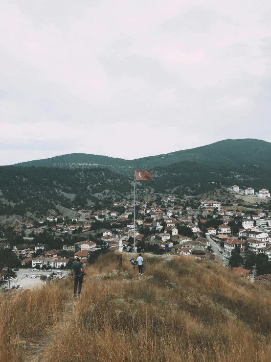 a group of people standing on top of a hill, by Lucia Peka, pexels contest winner, happening, white buildings with red roofs, turkish and russian, instagram story, high point of view