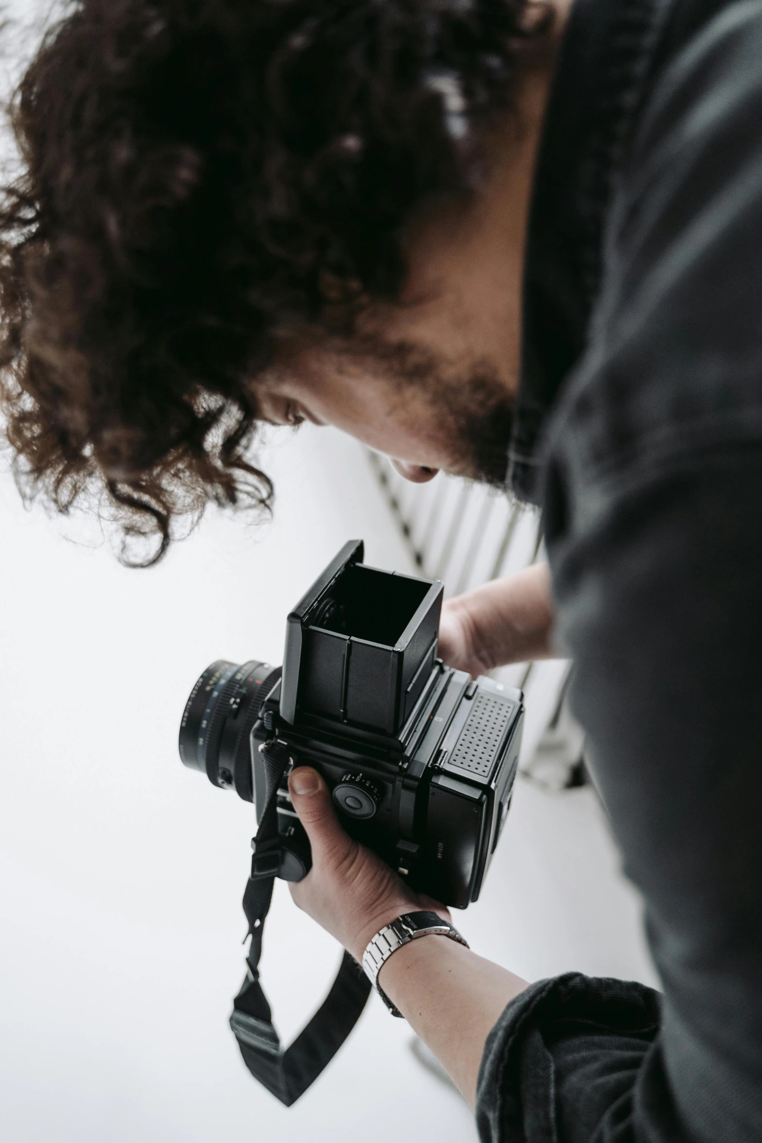 a man taking a picture with a camera, looking down on the camera, cinestill hasselblad 8 5 mm, over the shoulder shot, over-the-shoulder shot