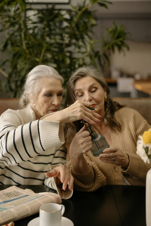 a couple of women sitting next to each other at a table, trending on pexels, renaissance, drinking cough syrup, gray haired, ( ( theatrical ) ), music video