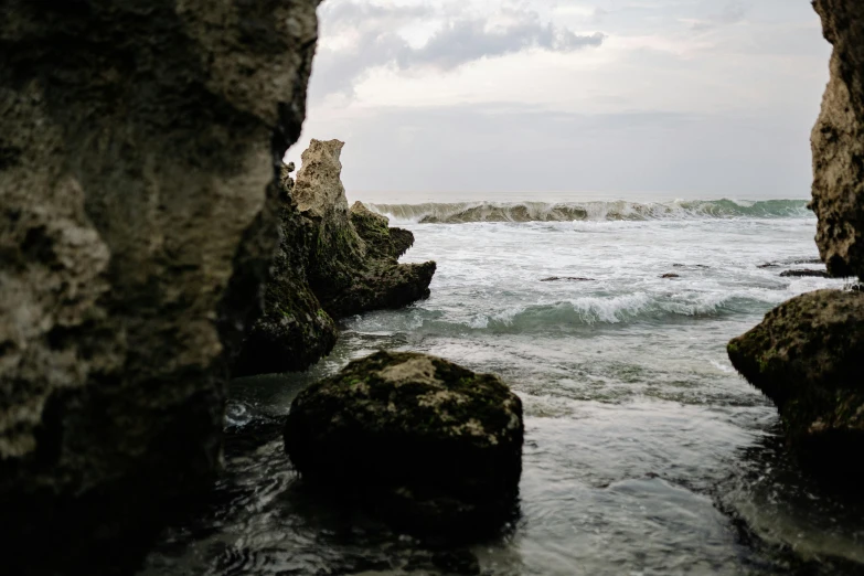 a view of the ocean from inside a cave, an album cover, unsplash, renaissance, limestone, medium format, bali, grey