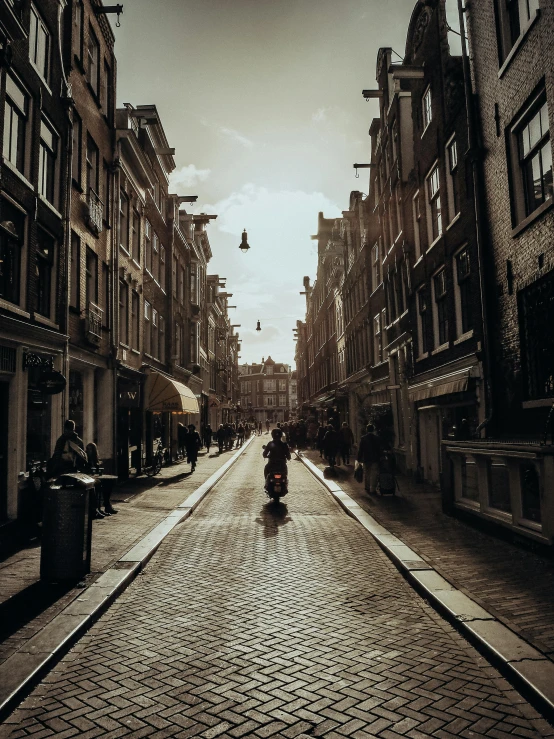 a man riding a motorcycle down a street next to tall buildings, by Thomas Wijck, pexels contest winner, baroque winding cobbled streets, dutch golden age, walking to the right, with a long