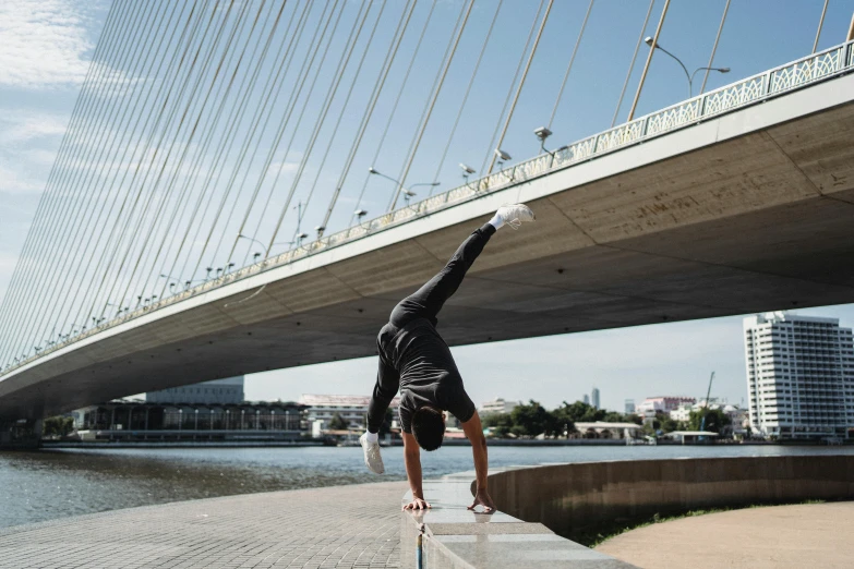 a man doing a handstand in front of a bridge, arabesque, icaro carvalho, profile image, thumbnail, high quality upload