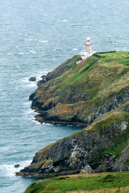 a couple of sheep standing on top of a lush green hillside, by David Donaldson, pexels contest winner, bold lighthouse in horizon, 2 5 6 x 2 5 6 pixels, warships, ireland