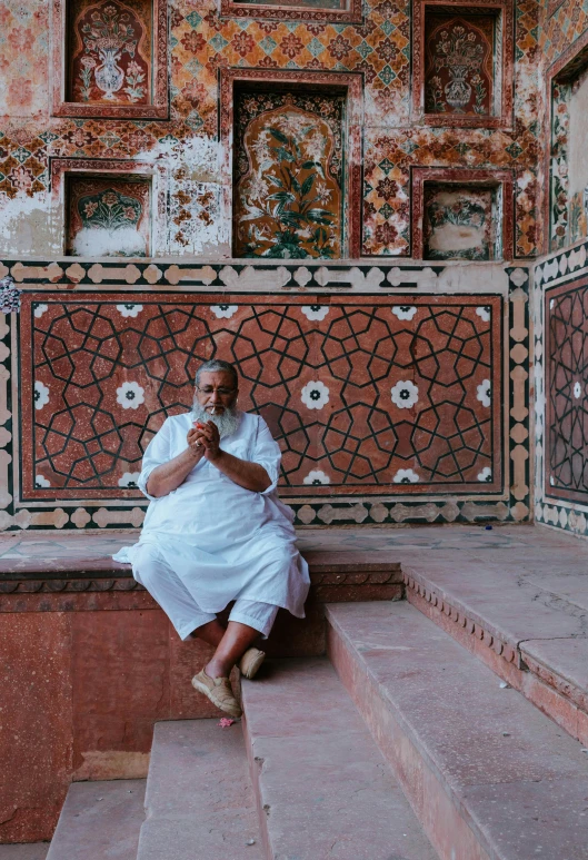 a man sitting on the steps of a building, inspired by Steve McCurry, pexels contest winner, symbolism, in front of a carved screen, mogul khan, inside a frame on a tiled wall, sitting in a lounge