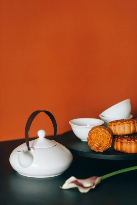 a close up of a plate of food on a table, a still life, inspired by Mi Fu, trending on unsplash, minimalism, teapots, crispy buns, orange theme, detailed product image