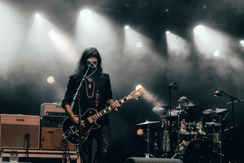 a man that is playing a guitar on a stage, pexels contest winner, with his long black hair, hazy, glares, asher duran