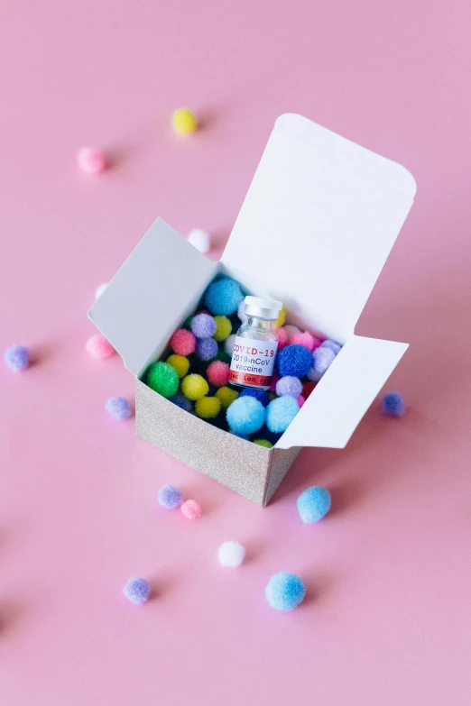 a box filled with candy sitting on top of a pink surface, vials, pink and blue and green mist, product shot, on a mini world