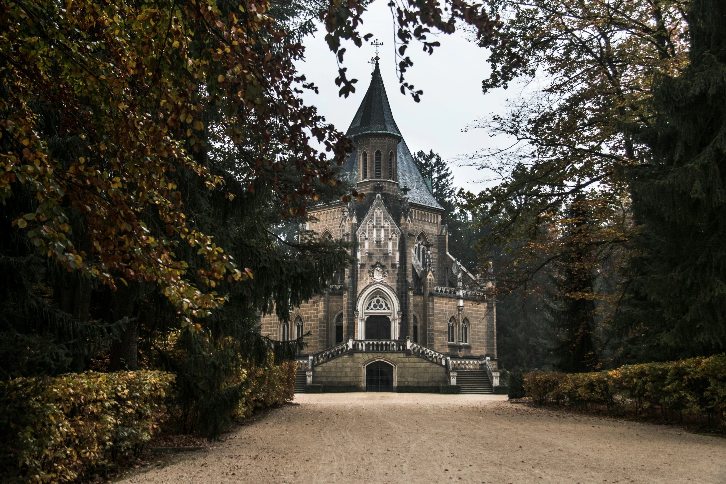 a large church sitting in the middle of a forest, a photo, by Adam Szentpétery, baroque, gothic revival, entrance, van, grey