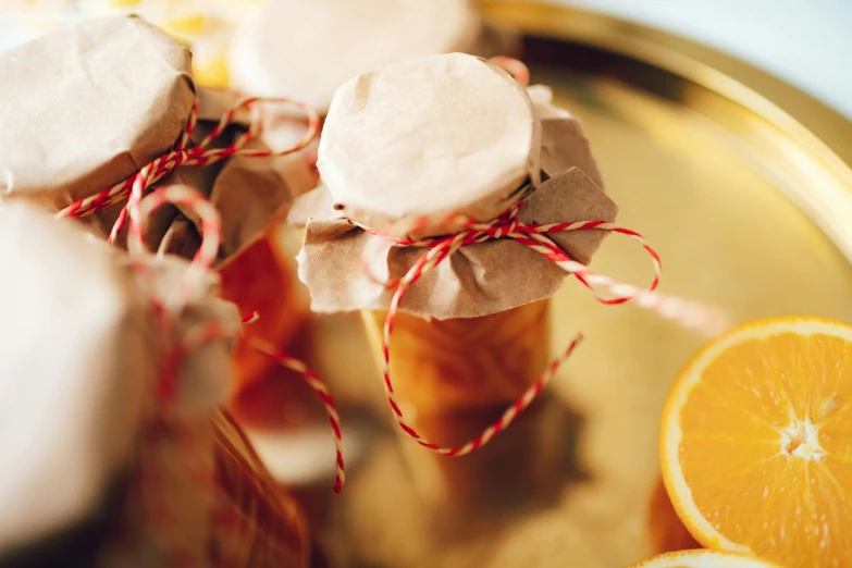 a silver tray topped with orange slices and jars of jam, by Alice Mason, pexels, dressed in red paper bags, festive, cream, thumbnail