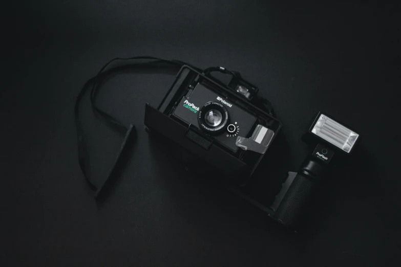 a camera sitting on top of a black table, a polaroid photo, black and teal paper, flash photo, unsplash photography, 90s photo