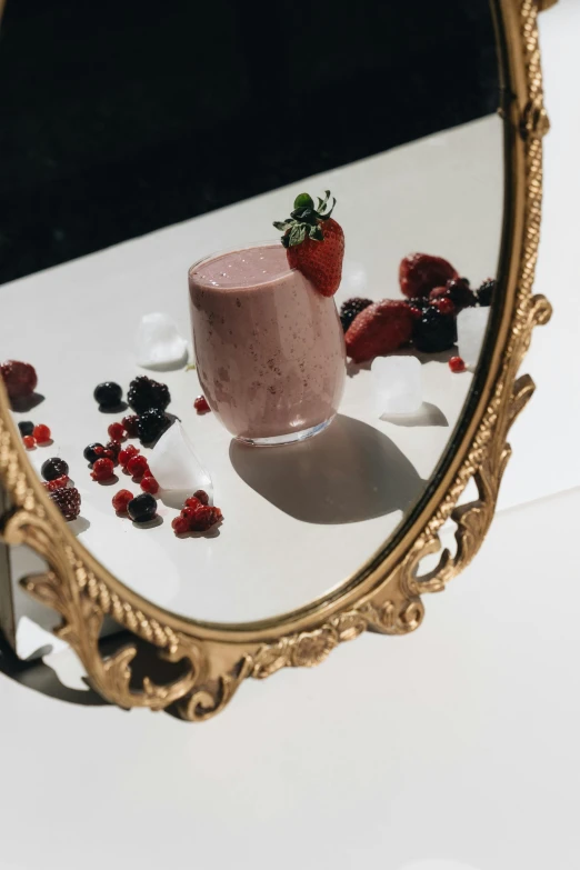 a close up of a mirror with a dessert in it, a still life, by Emma Andijewska, trending on pexels, renaissance, milkshake, berries, smooth oval shape face, gold