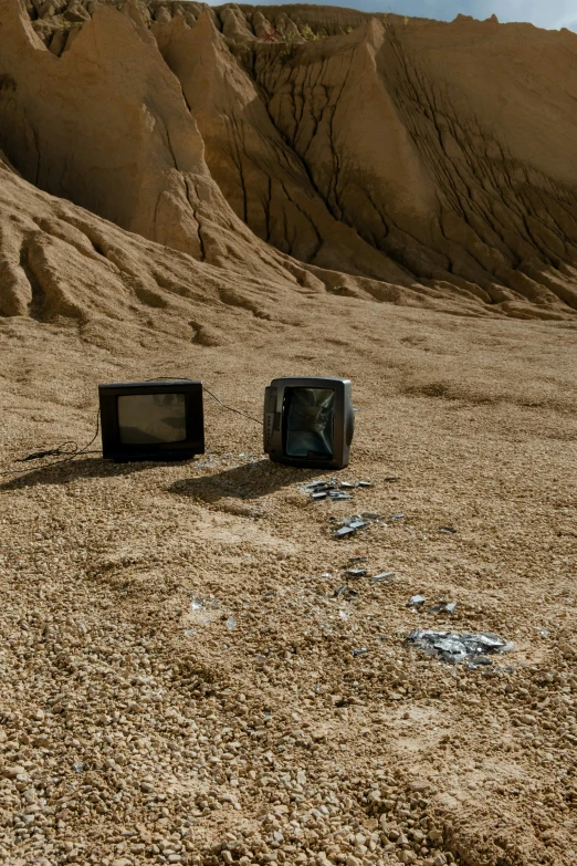 two televisions sitting in the middle of a desert, inspired by Wolf Vostell, unsplash, video art, erosion, cardboard, on moon, still from a live action movie