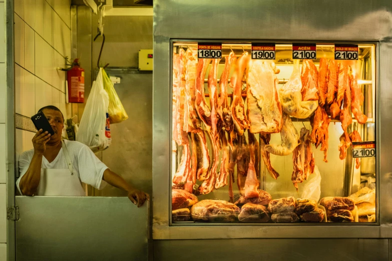 a man standing in front of a meat stand talking on a cell phone, by Peter Churcher, pexels contest winner, fantastic realism, singapore, square, fan favorite, profile image