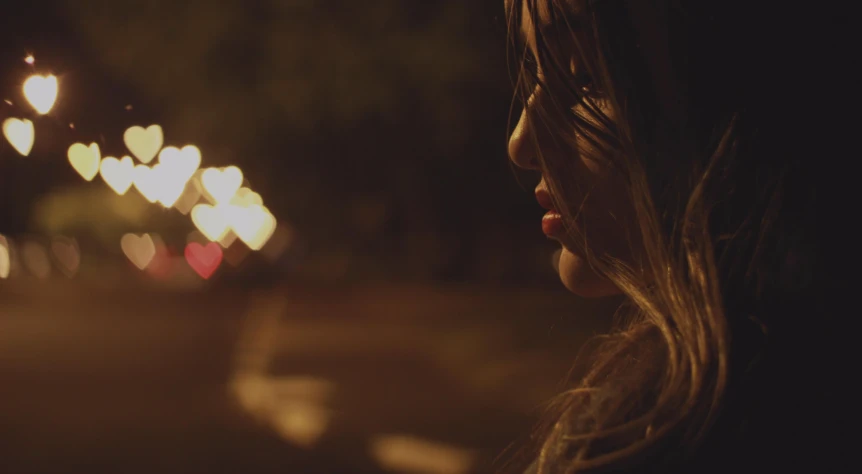 a woman standing in the middle of a street at night, trending on pexels, realism, close - up profile face, girl in love, anamorphic bokeh, candlelit