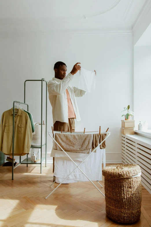 a woman ironing clothes on a clothes rack, by Matija Jama, pexels contest winner, renaissance, black man, in a white boho style studio, handsome man, inspect in inventory image