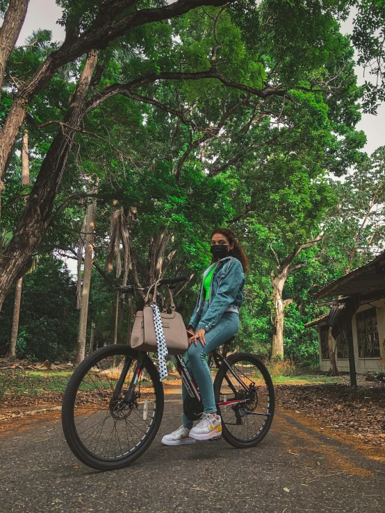 a woman sitting on a bike in the middle of the road, lush green forest, profile image, full body photo, wearing facemask and sunglasses