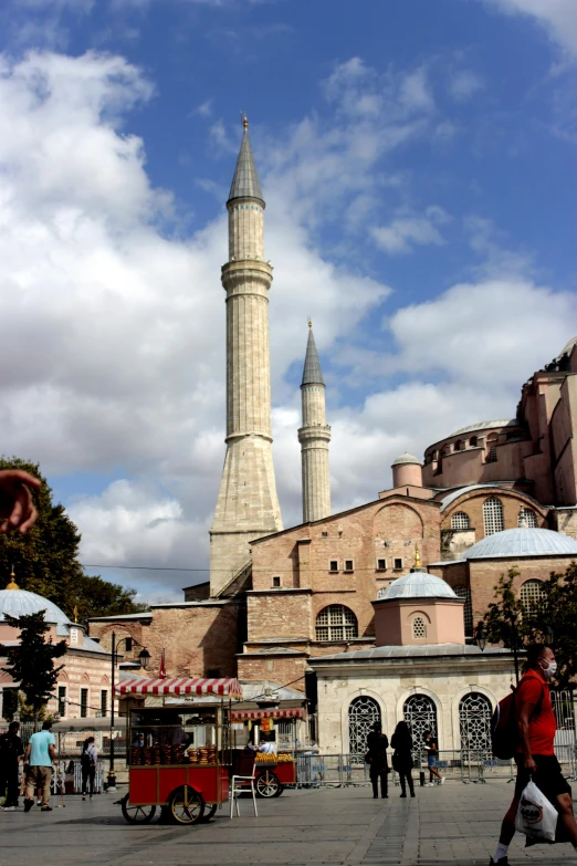 a group of people walking in front of a large building, minarets, byzantine ruins, restaurant in background, square