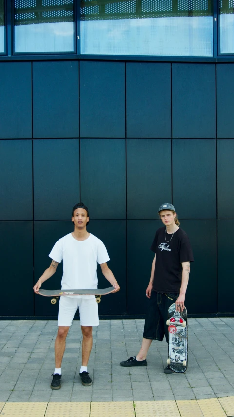 a couple of men standing next to each other with skateboards, by Matthias Stom, teenagers, promotional image, white on black, small