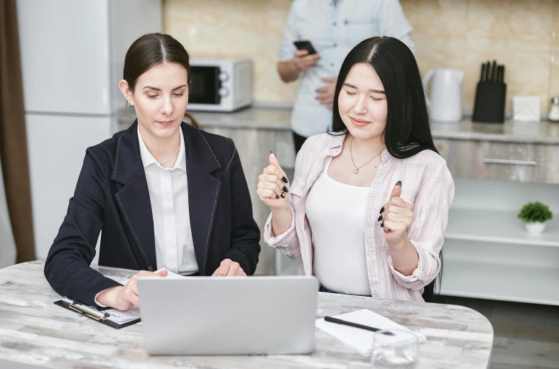 a couple of women sitting at a table with a laptop, trending on pexels, realism, giving a thumbs up, russian and japanese mix, professional profile picture, background image