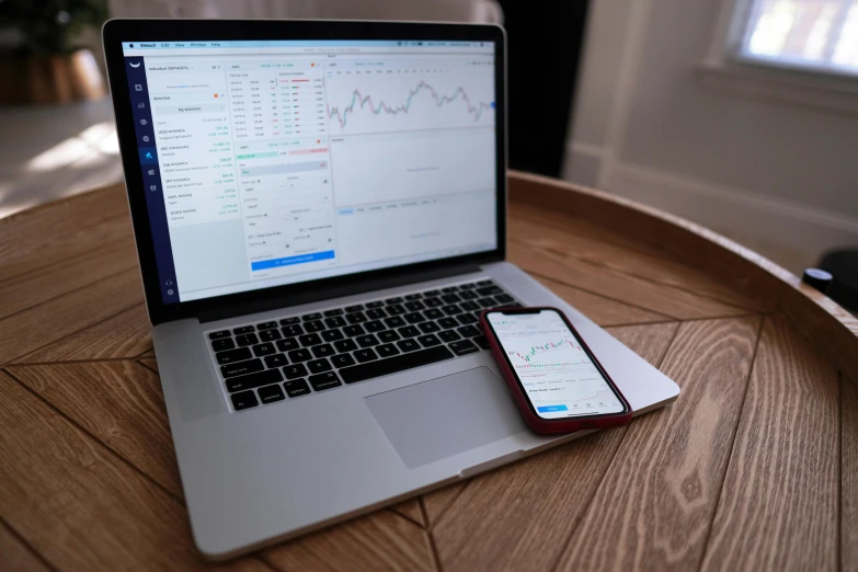 a laptop computer sitting on top of a wooden table, by Daniel Lieske, trending on pexels, analytical art, car trading game, crypto, taken on an iphone, graph signals