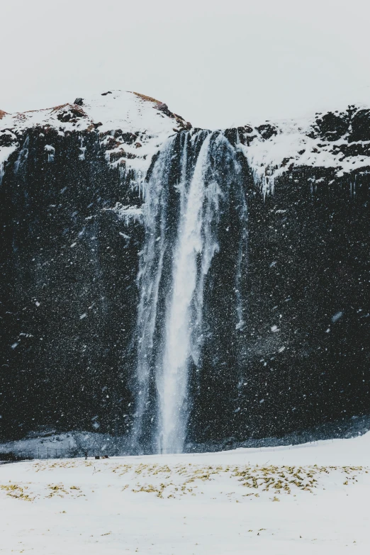 a man standing in front of a waterfall in the snow, pexels contest winner, hurufiyya, plain background, hydration, black, viewed from afar