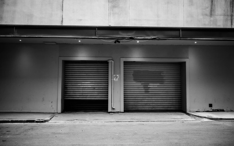a black and white photo of two garage doors, a black and white photo, by Daniel Gelon, unsplash, ffffound, north melbourne street, shuttered mall store, hiding