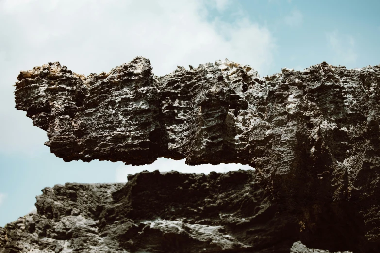 a close up of a rock with a sky background, unsplash, surrealism, dry archways, made of lava, ignant, big island