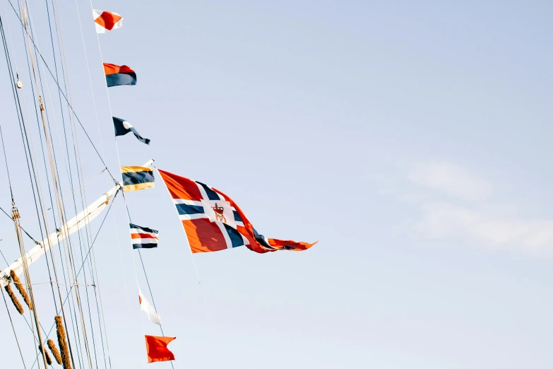 a bunch of flags that are flying in the air, by Jesper Knudsen, unsplash, hurufiyya, sea cloud, orange and blue, ignant, nordic crown