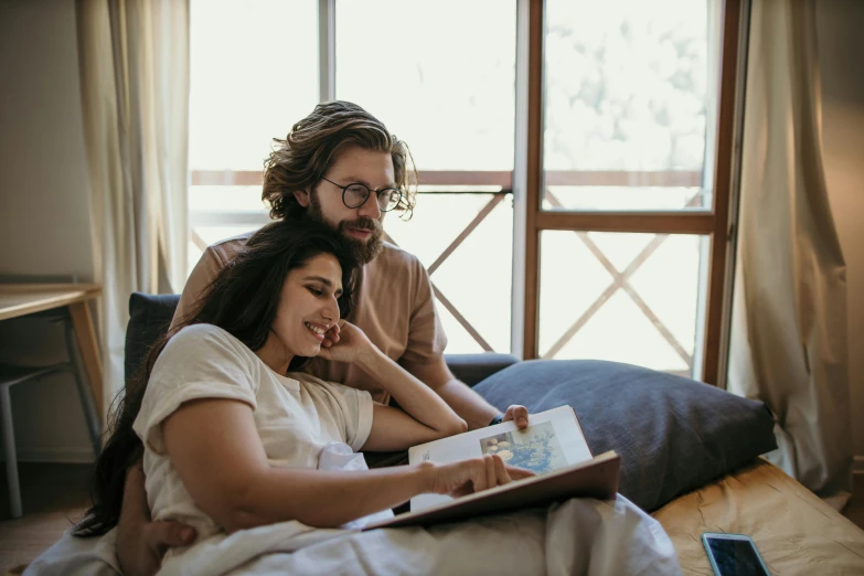 a man and woman sitting on a bed reading a book, pexels contest winner, australian, avatar image, sitting on couch, romantic lead