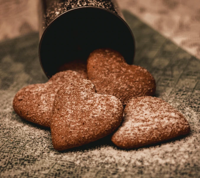 a couple of heart shaped cookies sitting on top of a table, by Emma Andijewska, pexels, powdered sugar, brown, nostalgic melancholy, thumbnail