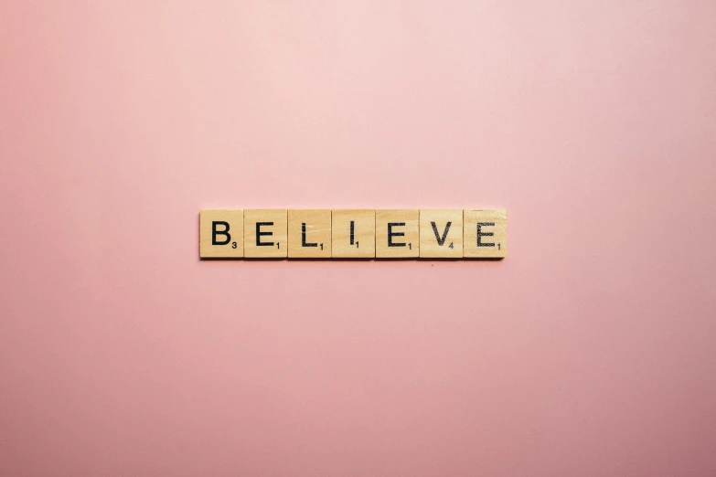 the word believe spelled with scrabbles on a pink background, a picture, inspired by Henri Bellechose, trending on pexels, wall ], but minimalist, christian saint, belly