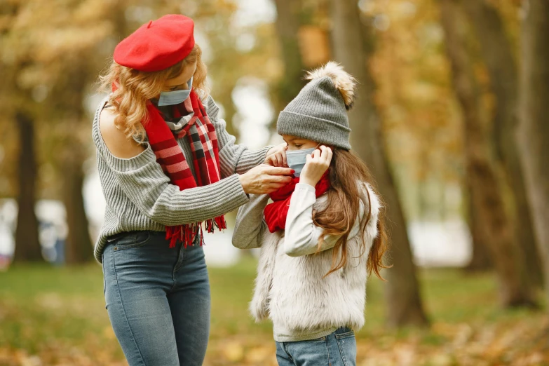 a woman talking on a cell phone next to a little girl, a picture, by Julia Pishtar, shutterstock, autumnal, surgical mask covering mouth, red ascot and a field cap, red sweater and gray pants