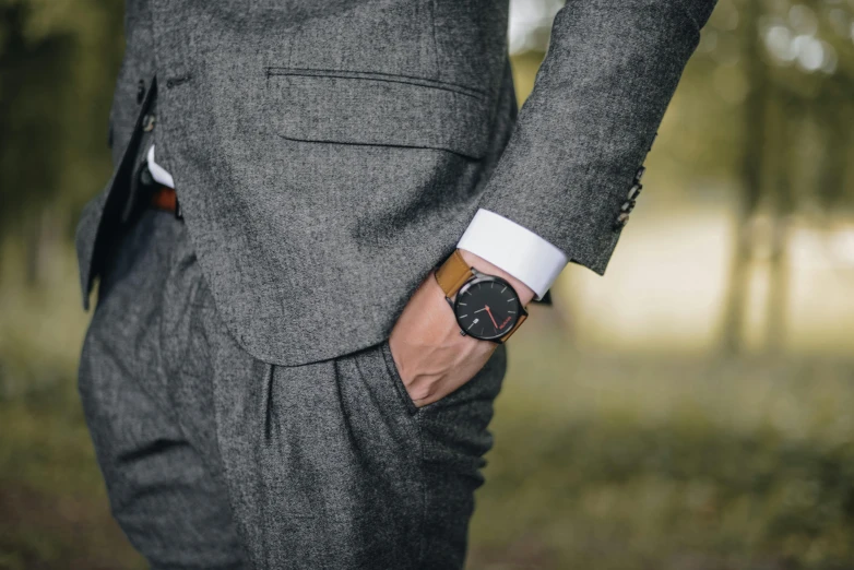 a man in a suit with a watch on his wrist, pexels, renaissance, dark grey and orange colours, tan suit, wearing a plug suit, thumbnail