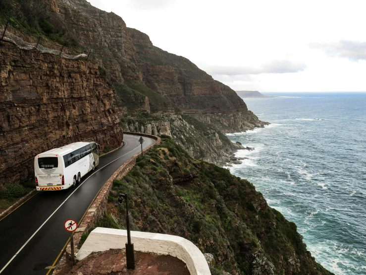 a white bus driving down a road next to the ocean, by Tom Wänerstrand, pexels contest winner, renaissance, sharp cliffs, south african coast, 2 5 6 x 2 5 6 pixels, 💋 💄 👠 👗