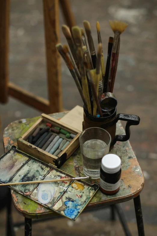 a table that has a bunch of art supplies on it, a photorealistic painting, inspired by Art Brenner, unsplash, process art, aged 2 5, in a workshop, medium close up shot, ilustration