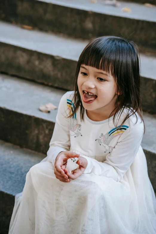 a little girl in a white dress sitting on some steps, inspired by Nara Yoshitomo, pexels contest winner, eating a rat, smiling playfully, children playing with pogs, long sleeves