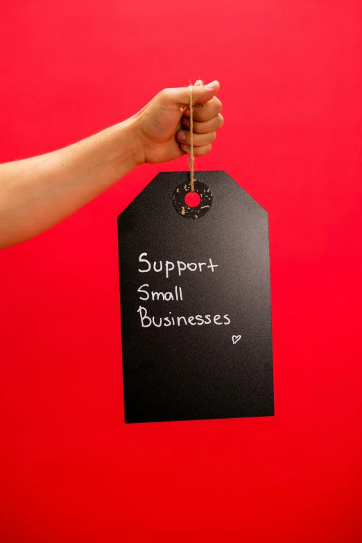 a person holding a sign that says support small businesses, an album cover, pexels, square, red ribbon, blackboard, dark. no text