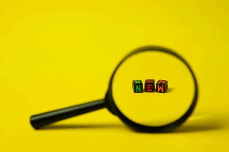 a magnifying glass with a word next to it, a picture, trending on pexels, new objectivity, yellow, small square glasses, tilt-shifted, a new